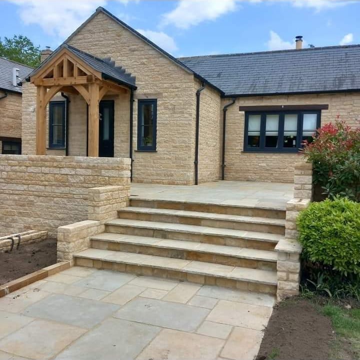 Stepped sandstone patio with stone porch by Advanced Builders